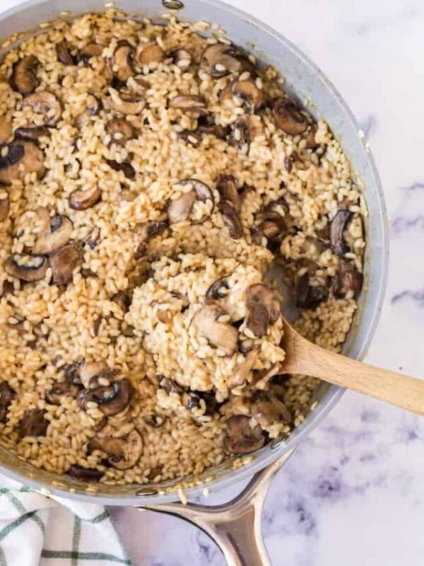 a pot of mushroom risotto cooking and a wooden spoon