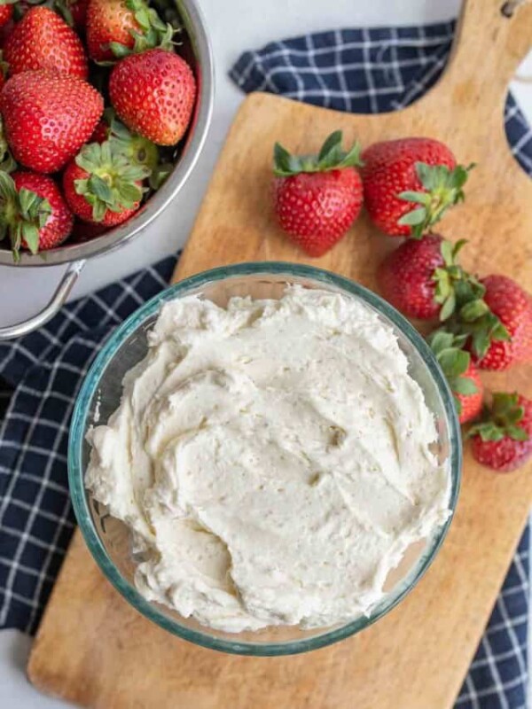 Bowl of chantilly cream with strawberries nearby