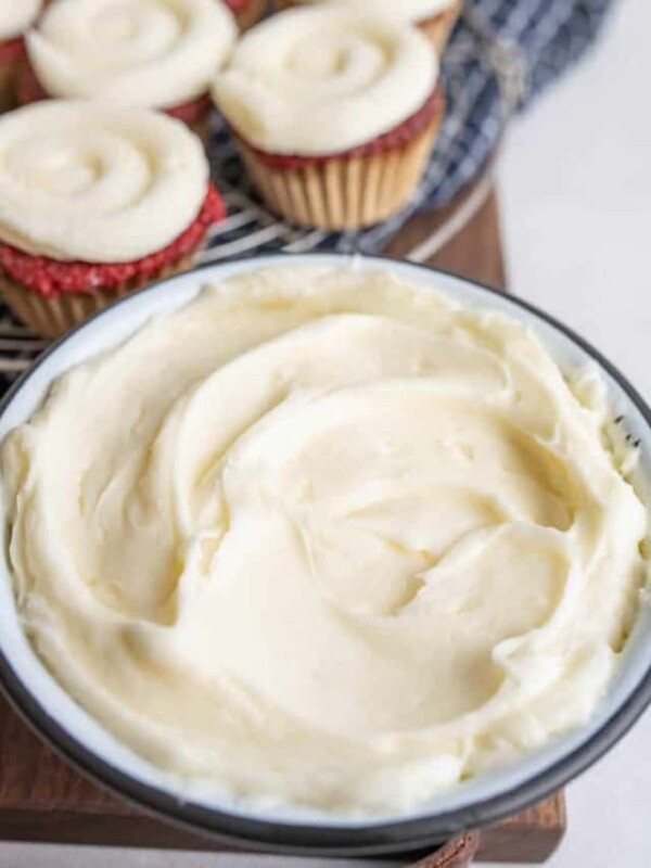 fluffy cream cheese frosting in a bowl and piped onto rd velvet cupcakes