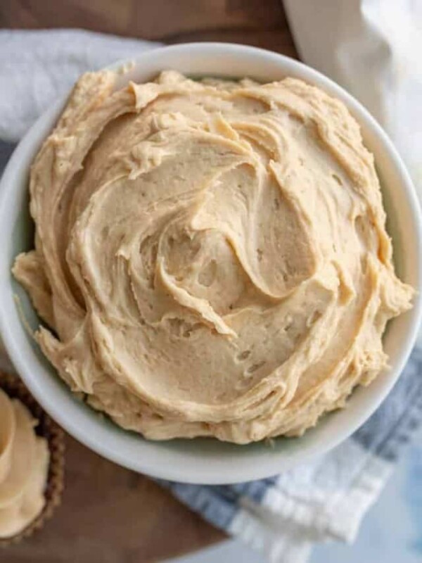 top view of fluffy peanut butter frosting in a bowl with whipped beige peaks