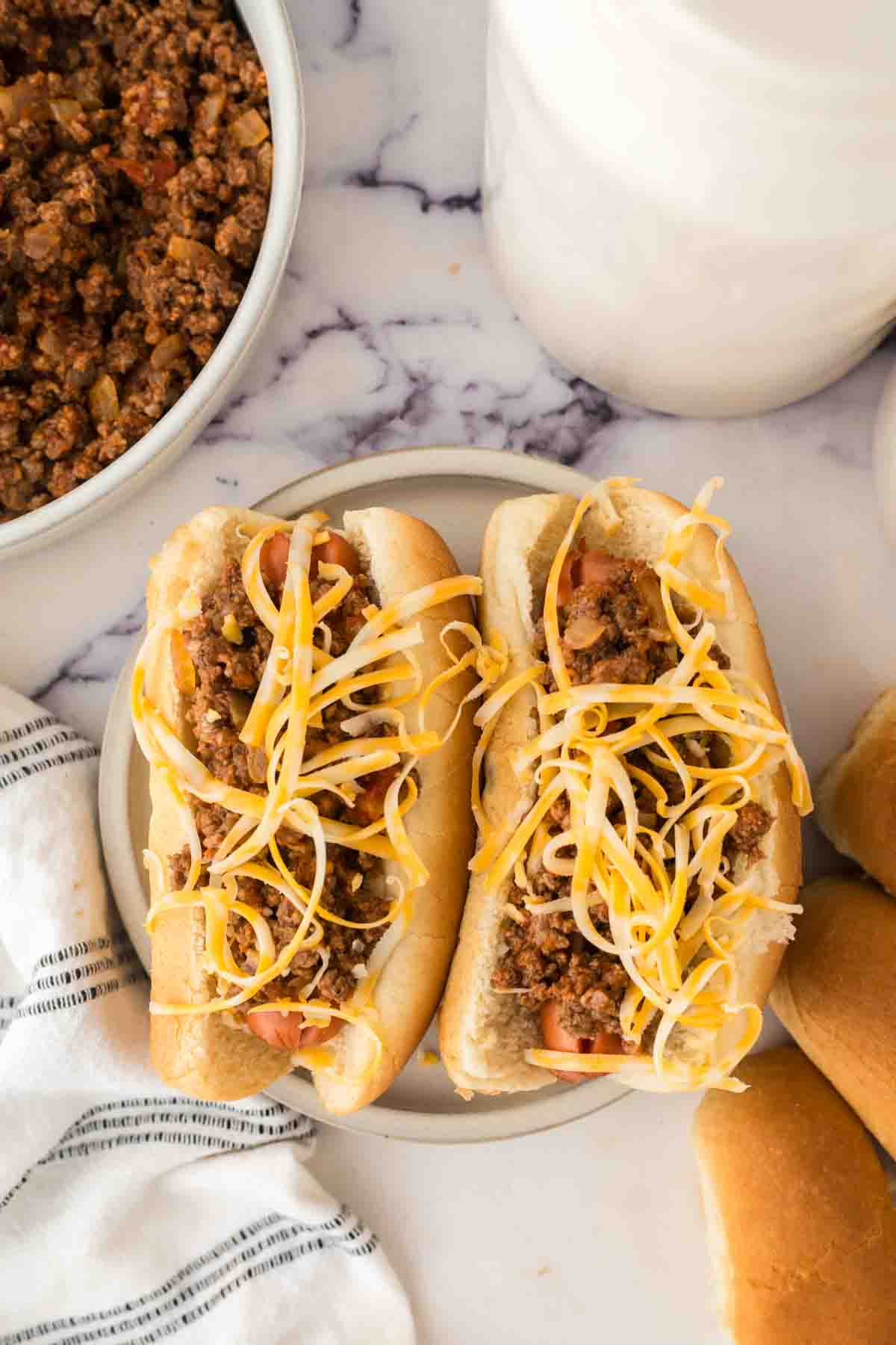 top view of two chili dogs on a plate.