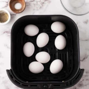 whole eggs in a black deep fryer basket.