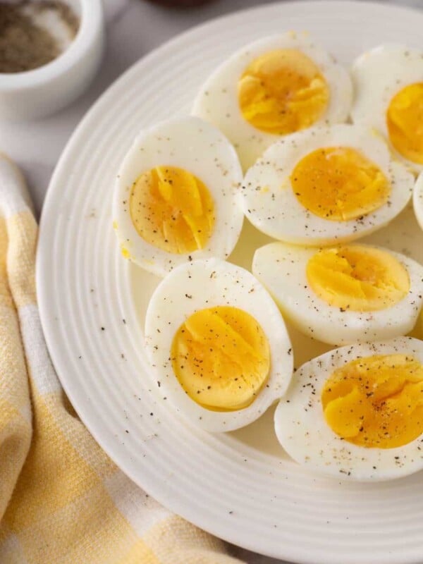 halved seasoned air fryer cooked eggs with sale and pepper on a white plate.