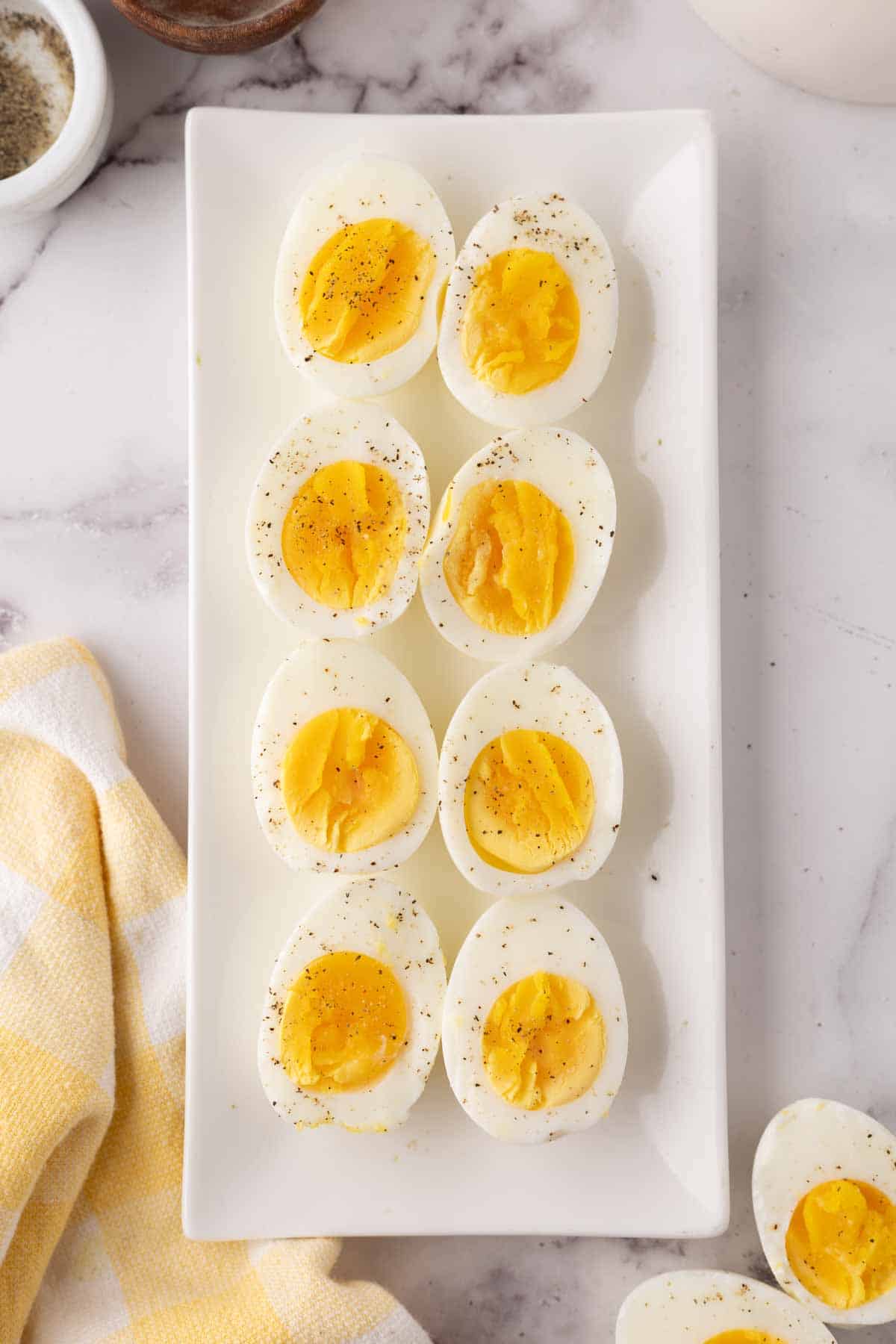 halved seasoned air fryer cooked eggs with sale and pepper on a white plate.