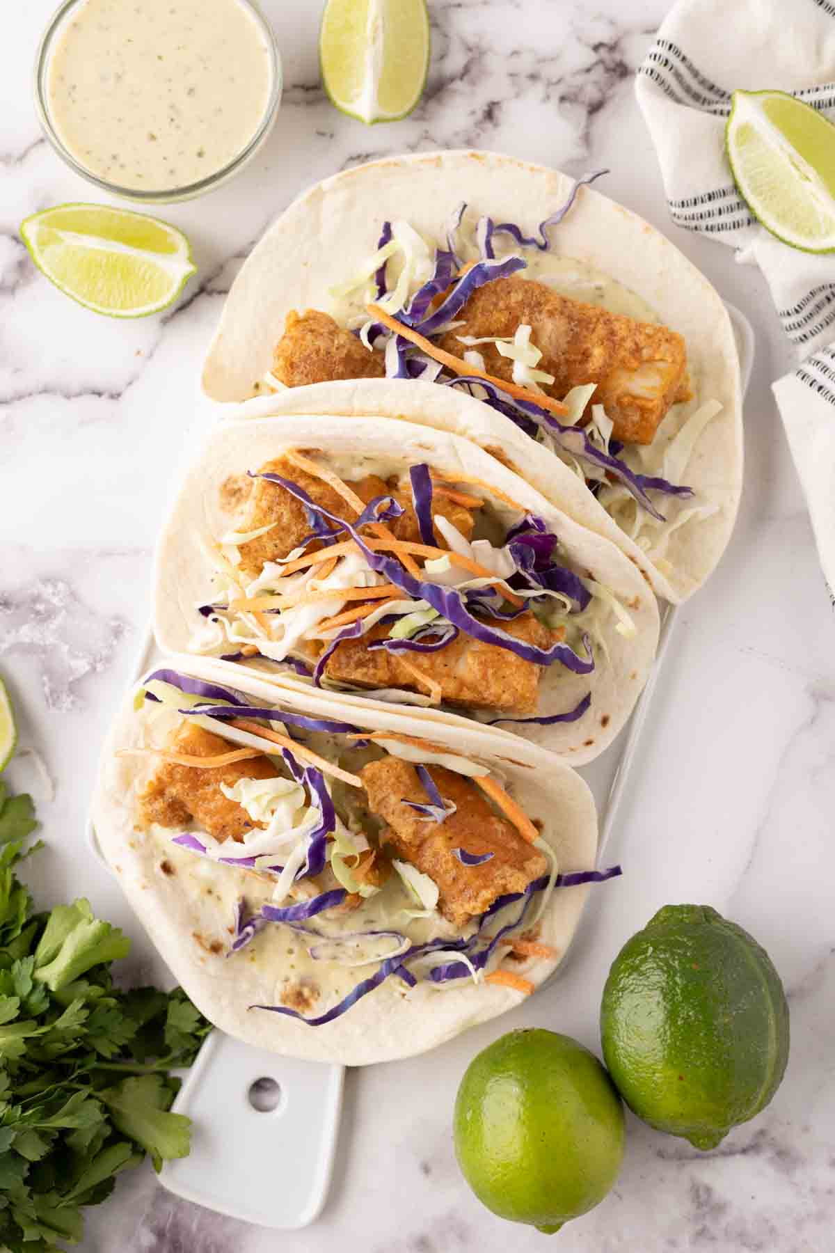 deep fried baja fish taco recipe with cabbage on a flour tortilla with limes.