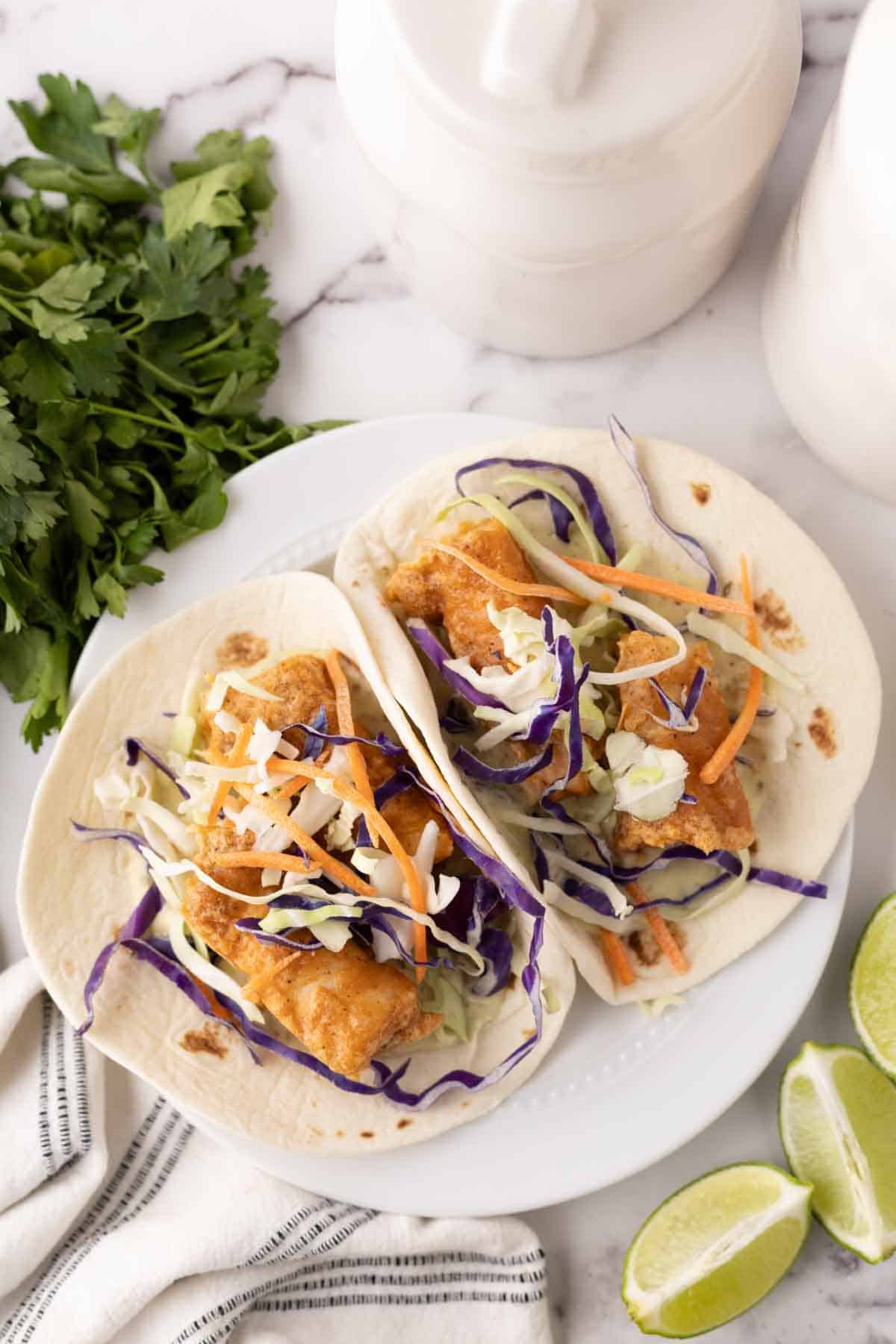 deep fried baja fish taco recipe with cabbage on a flour tortilla with limes.