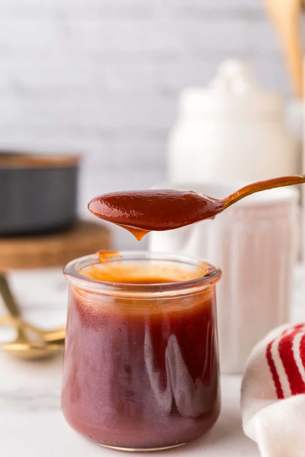 small glass jar with a golden spoon above with barbecue sauce recipe.