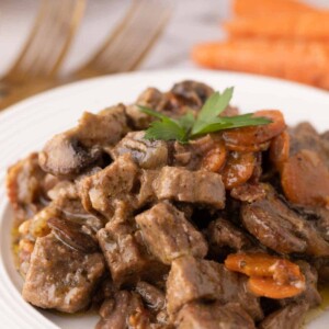 Beef Bourguignon Recipe served on a white plate with golden forks.