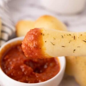 one bosco stick dipped into a small bowl of red sauce.