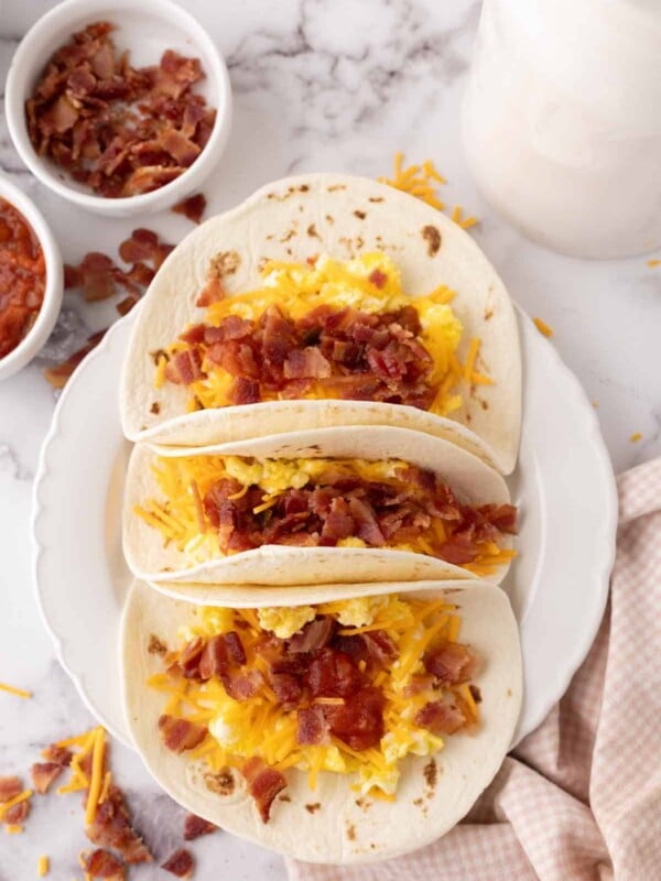 breakfast tacos with eggs cheese bacon on three flour tortillas.
