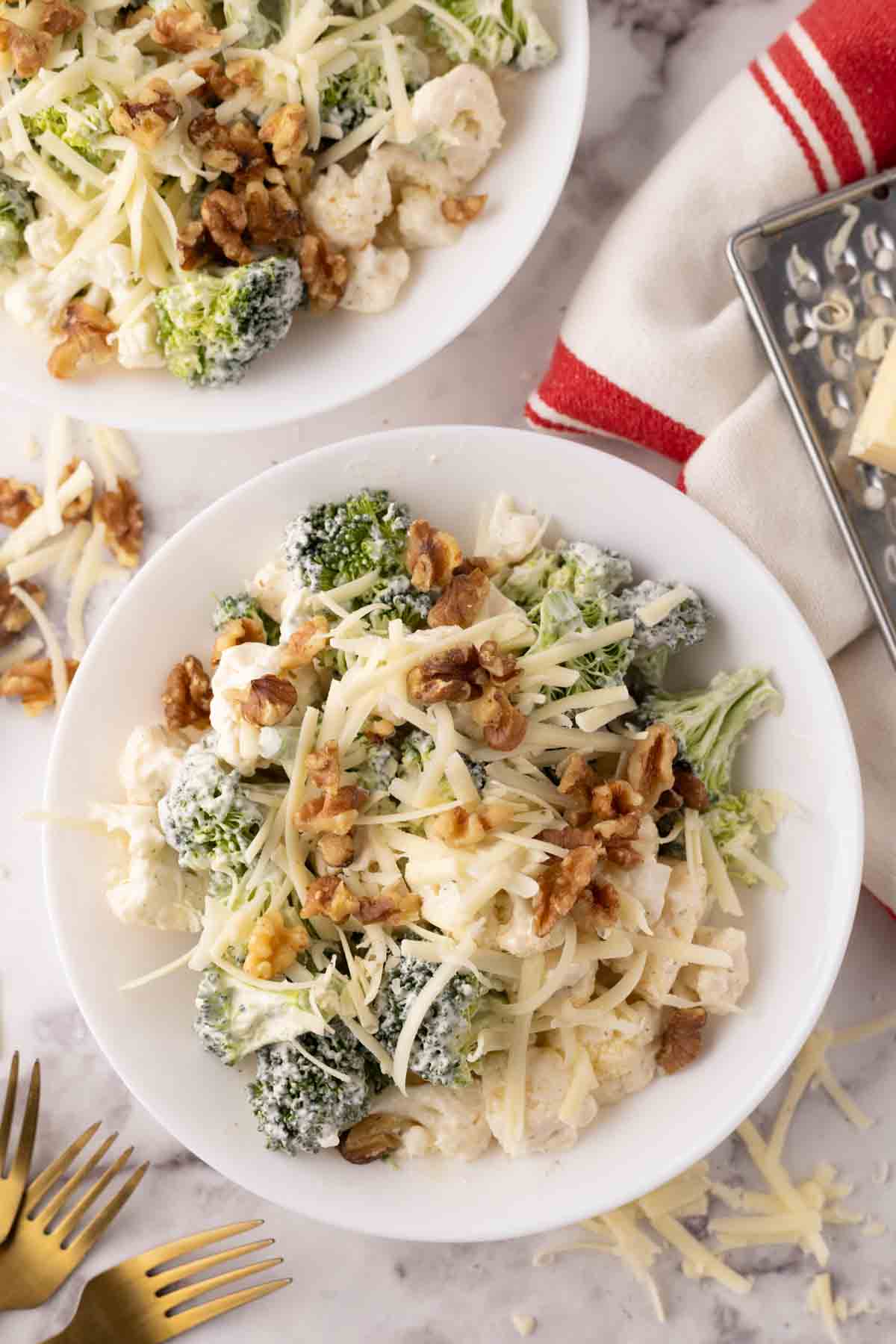 broccoli and cauliflower salad recipe with walnuts on white plates.