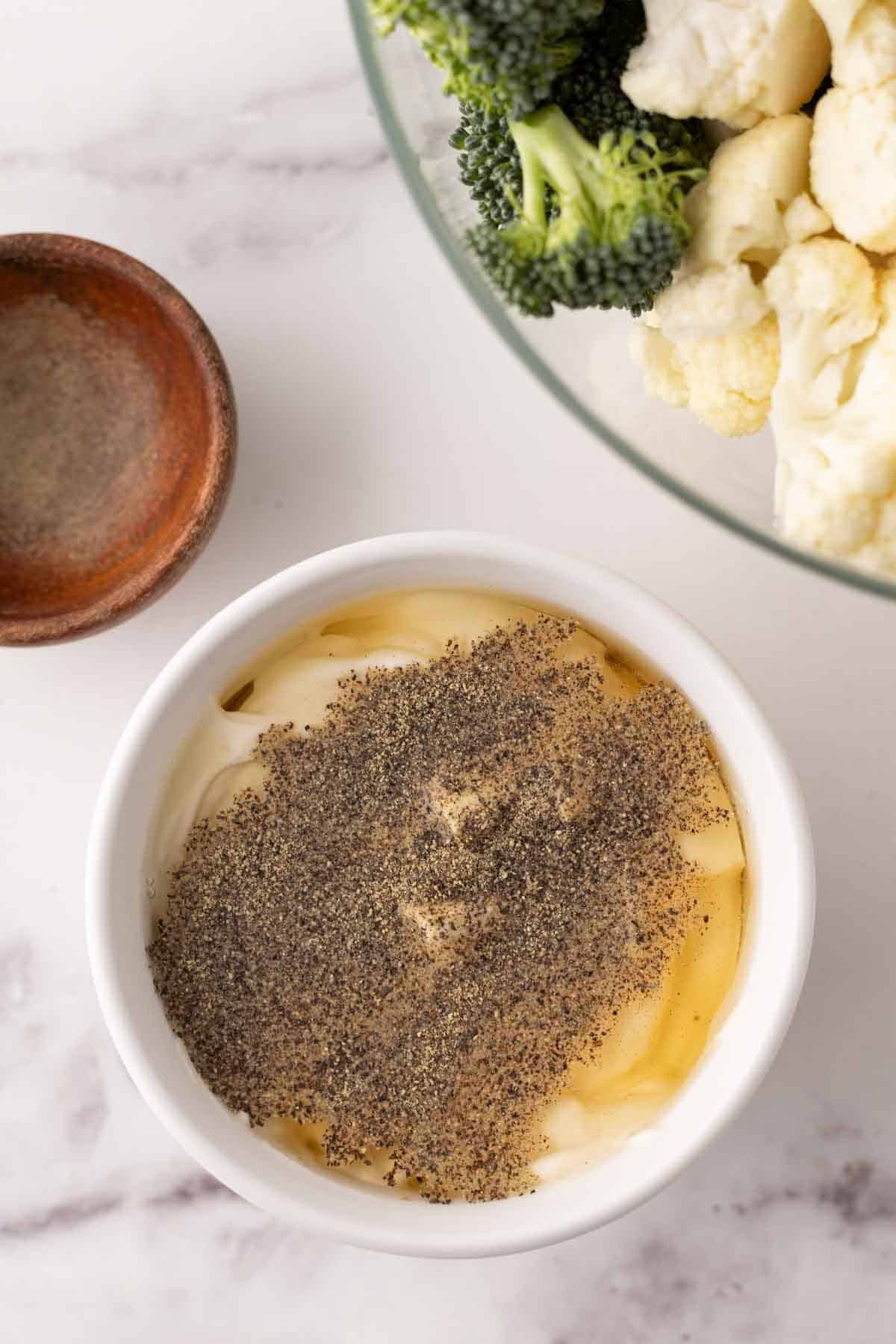 broccoli and cauliflower salad dressing in progress in a bowl.