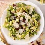 Brussels sprouts salad on a white plate with golden forks to the side.