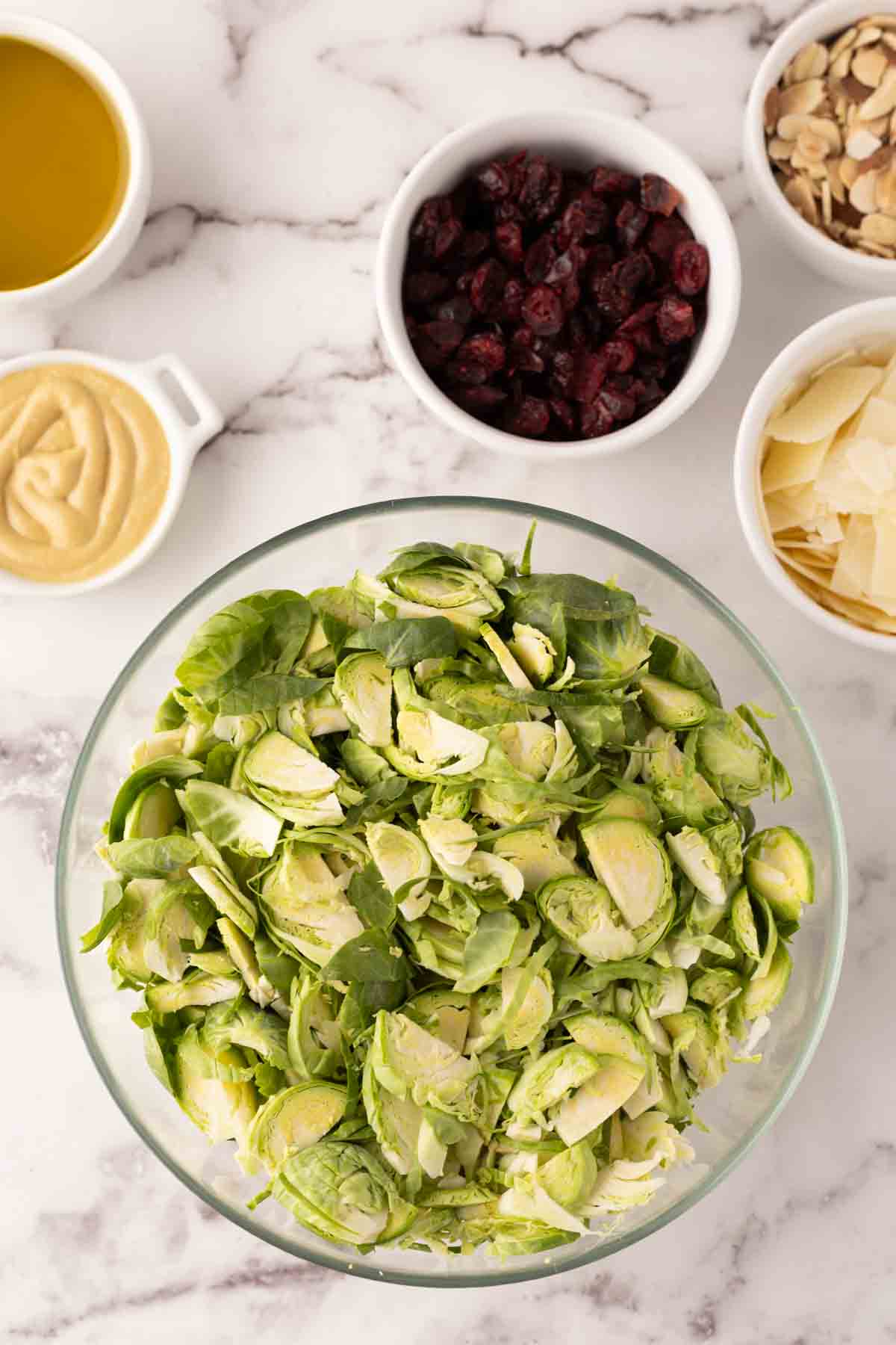 portion bowls each with raw ingredient to make Brussels sprouts salad recipes.