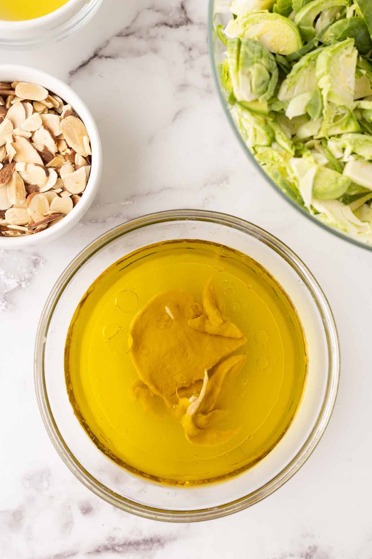 portion bowls each with raw ingredient to make Brussels sprouts salad recipes.