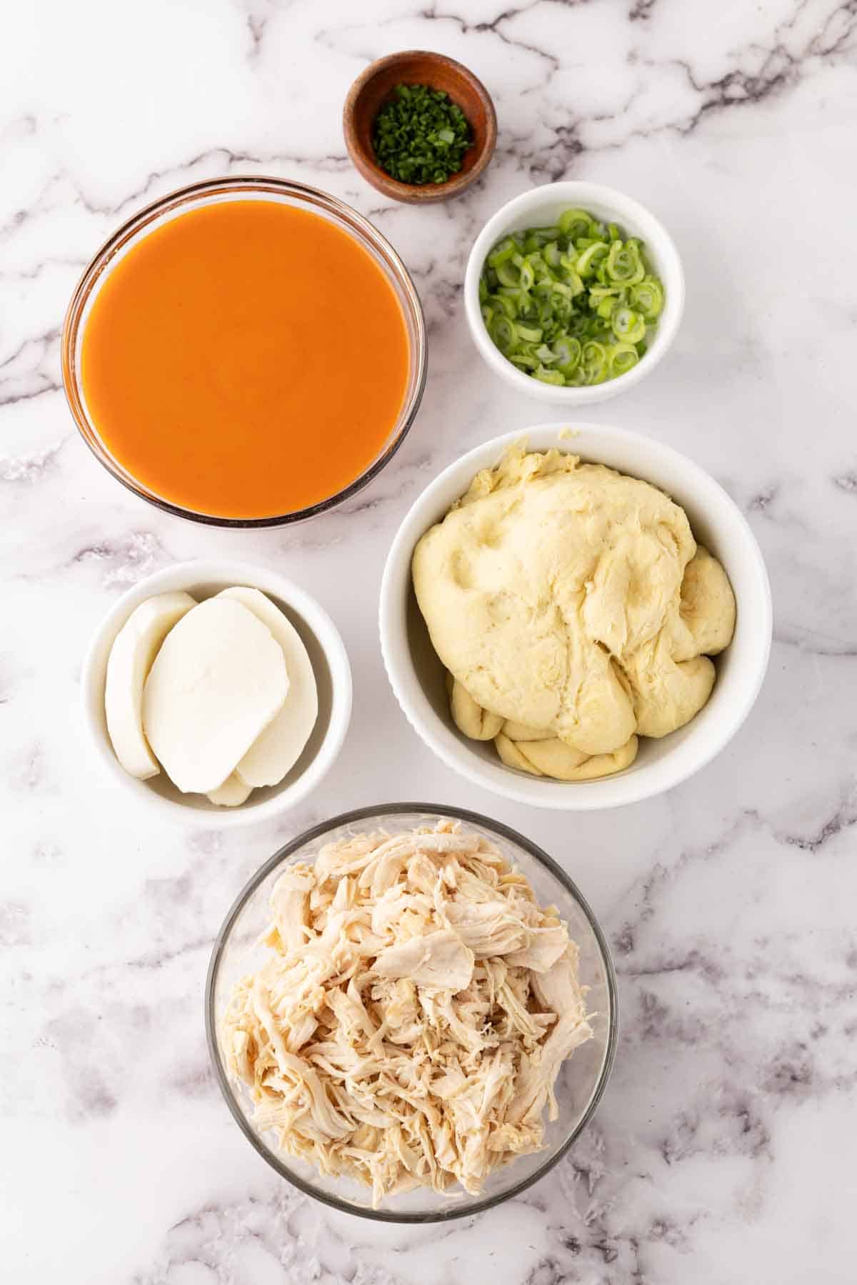 portion bowls each with raw ingredient to make buffalo pizza.