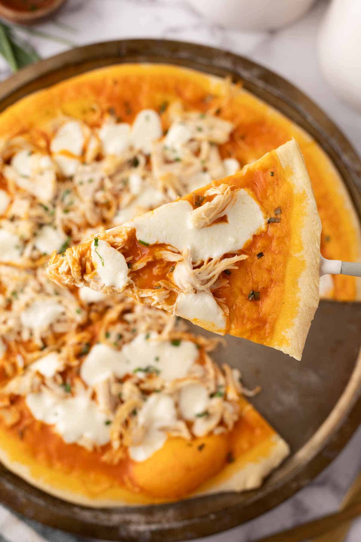 one slice of buffalo pizza with mozzarella and chicken on top on a spatula.