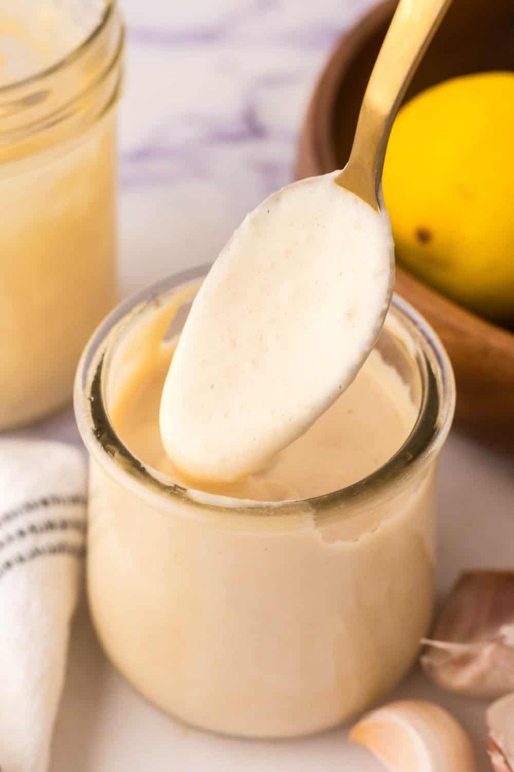 side view of homemade caesar dressing recipe in a small glass jar with a spoon