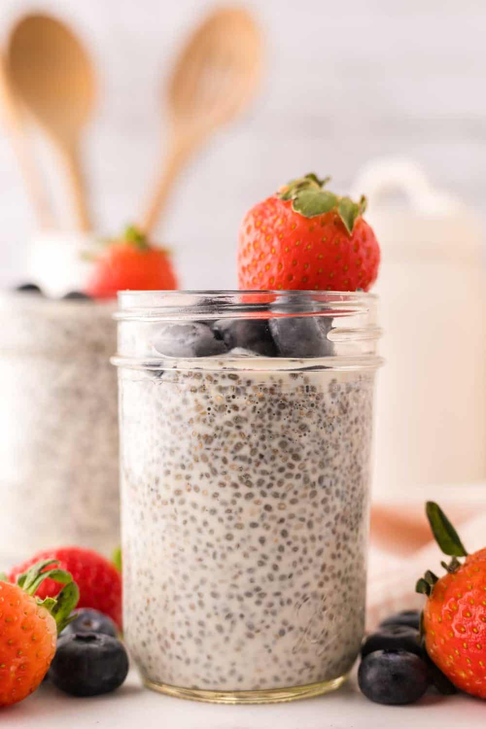 chia seed pudding in small mason jars with strawberries and blueberries.