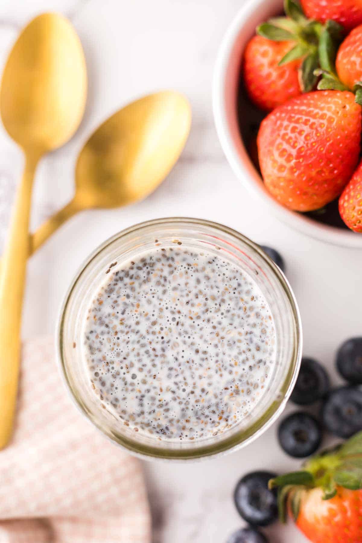 chia seed pudding in small mason jars with golden spoons to the side.