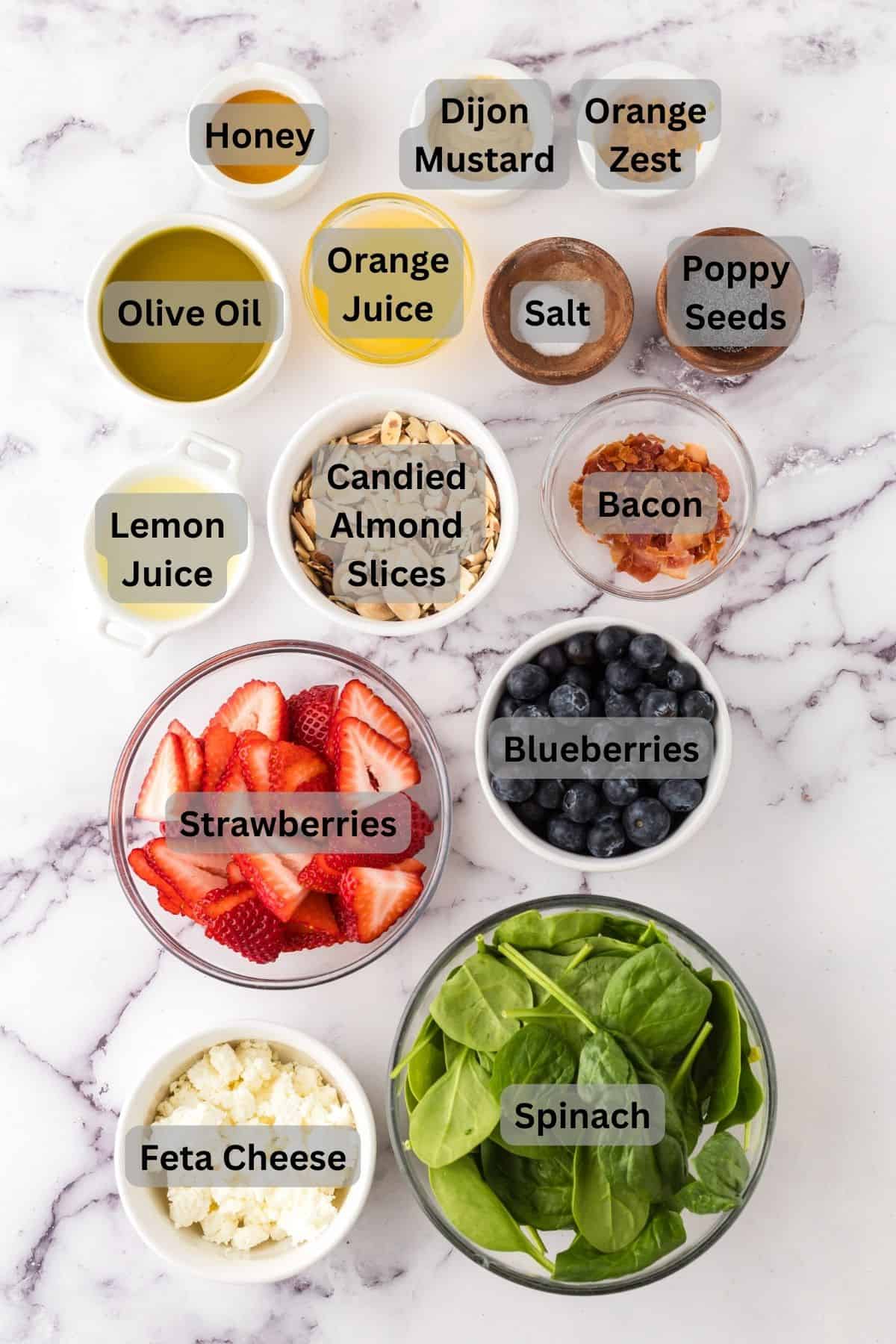 portion bowls each with digitally labeled raw ingredients to make berry spinach salad.