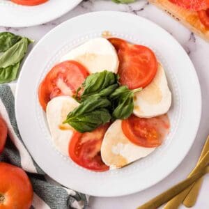 white plate with tomato basil and mozzarella for the caprese salad recipe.