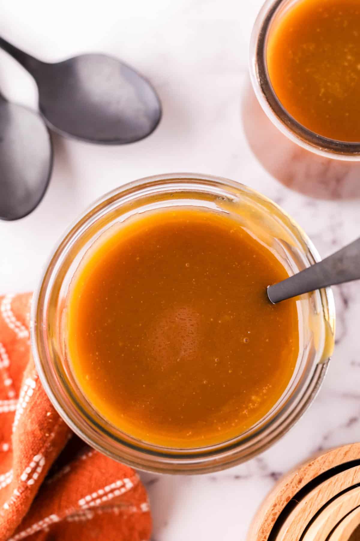 glass jar filled with homemade caramel sauce and a black spoon.