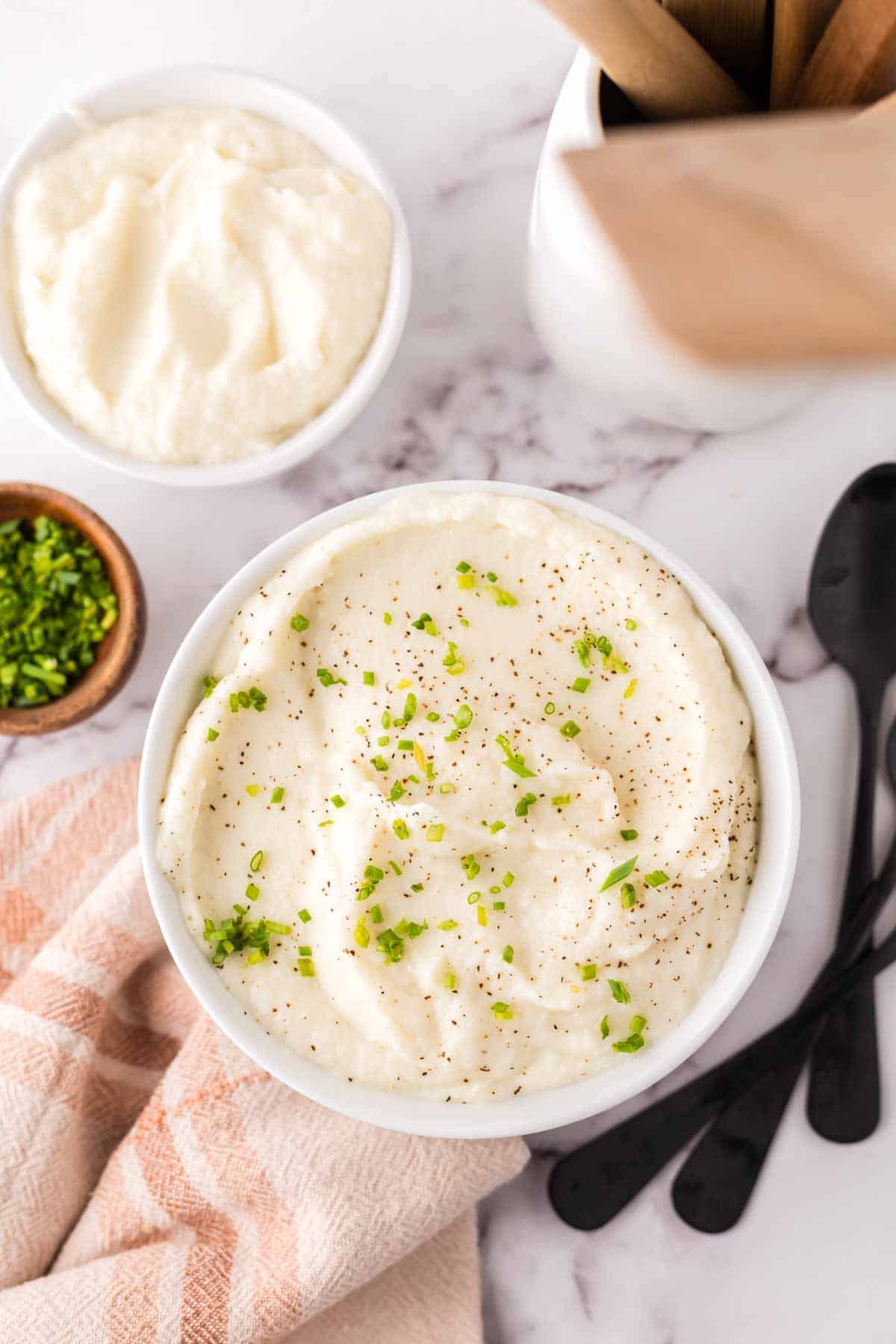 small white bowl with cauliflower mashed potatoes with seasonings on top.