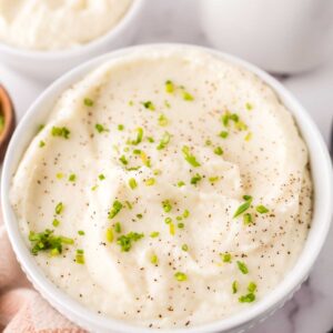 small white bowl with cauliflower mashed potatoes with seasonings on top.