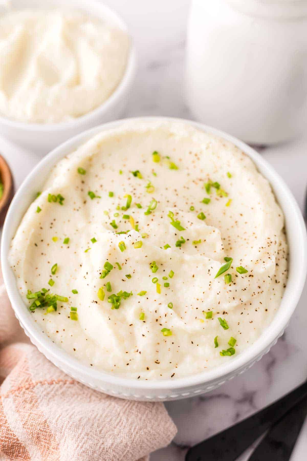 small white bowl with cauliflower mashed potatoes with seasonings on top.