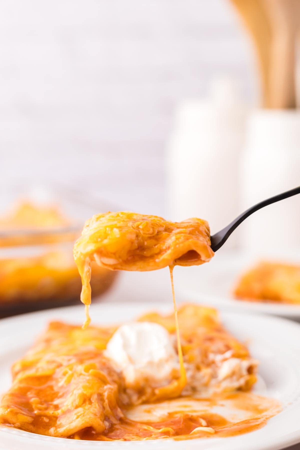 cheese enchiladas on a black fork ready to eat.