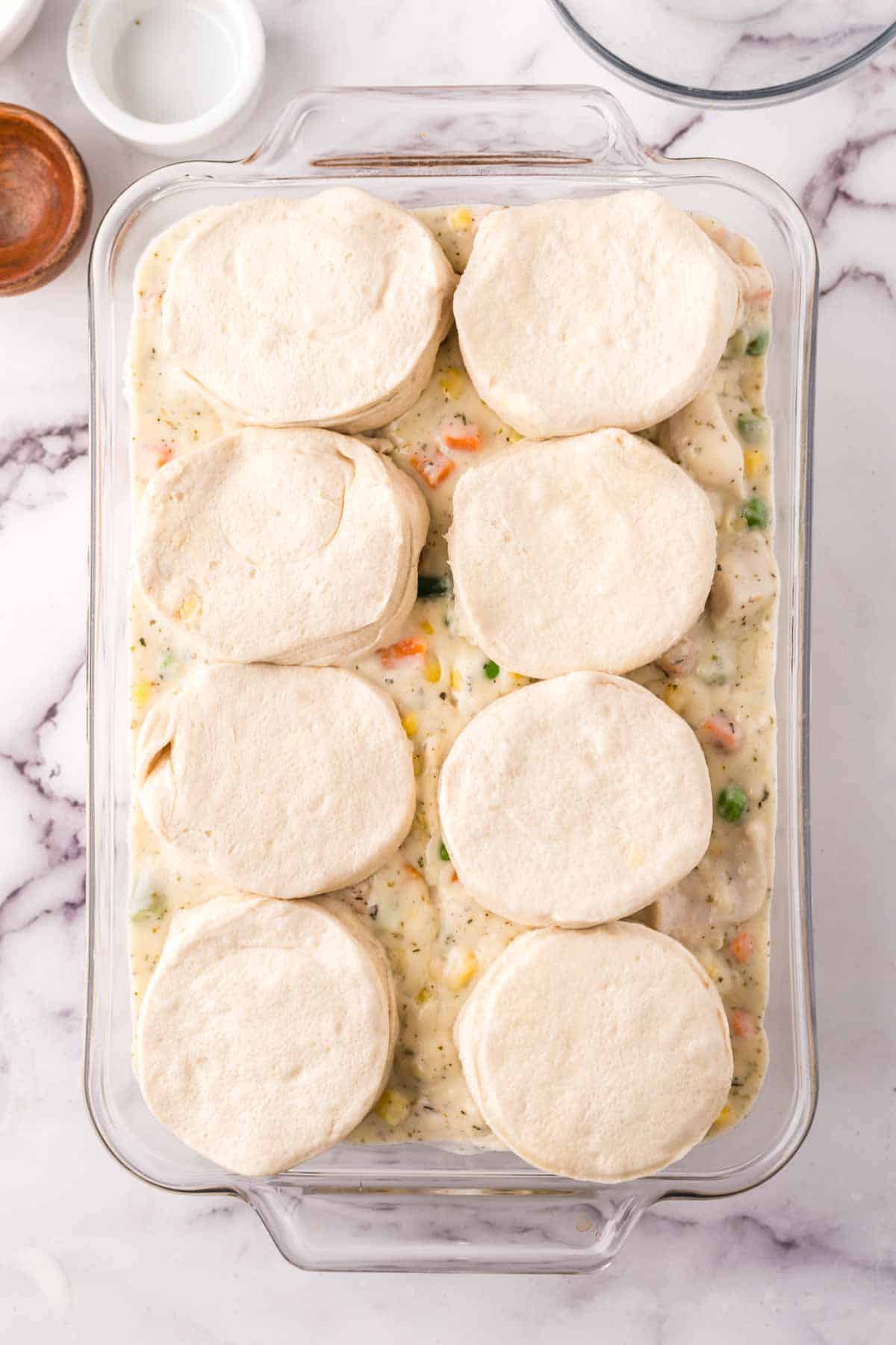 casserole dish with raw ingredients for chicken and biscuits recipe in progress.