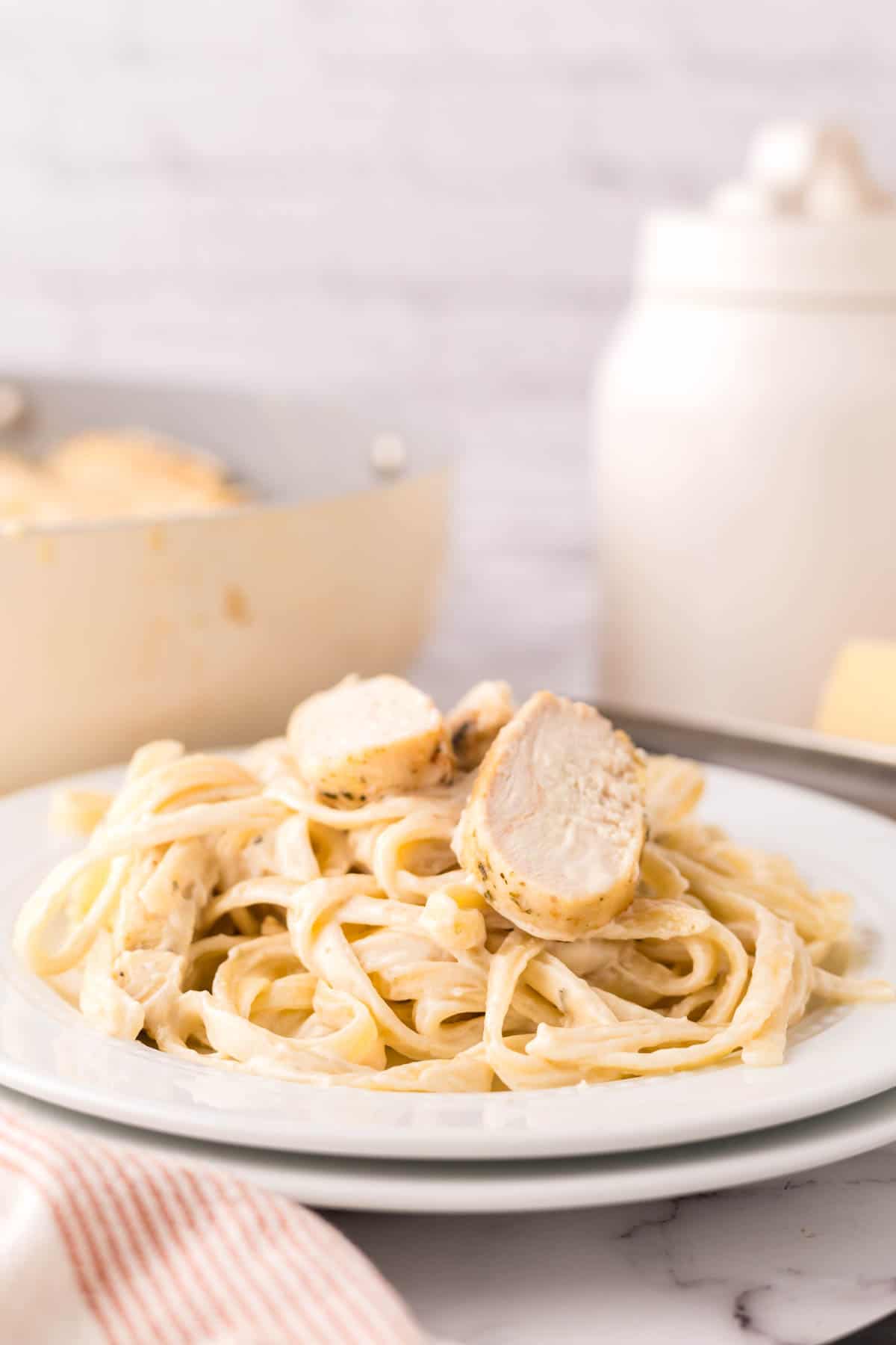 chicken fettuccine alfredo in a white serving bowl with parmesan cheese.