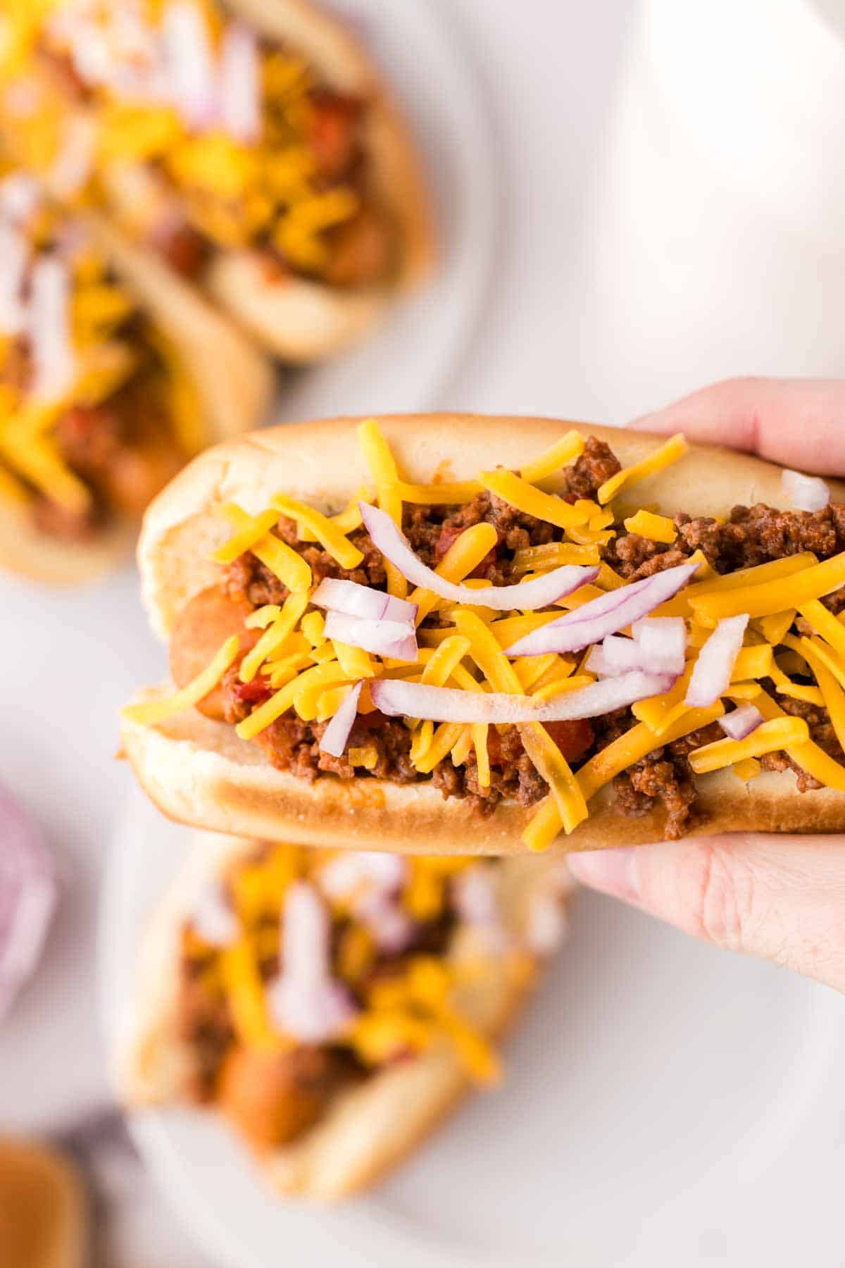 hand holding a chili dog ready to eat.