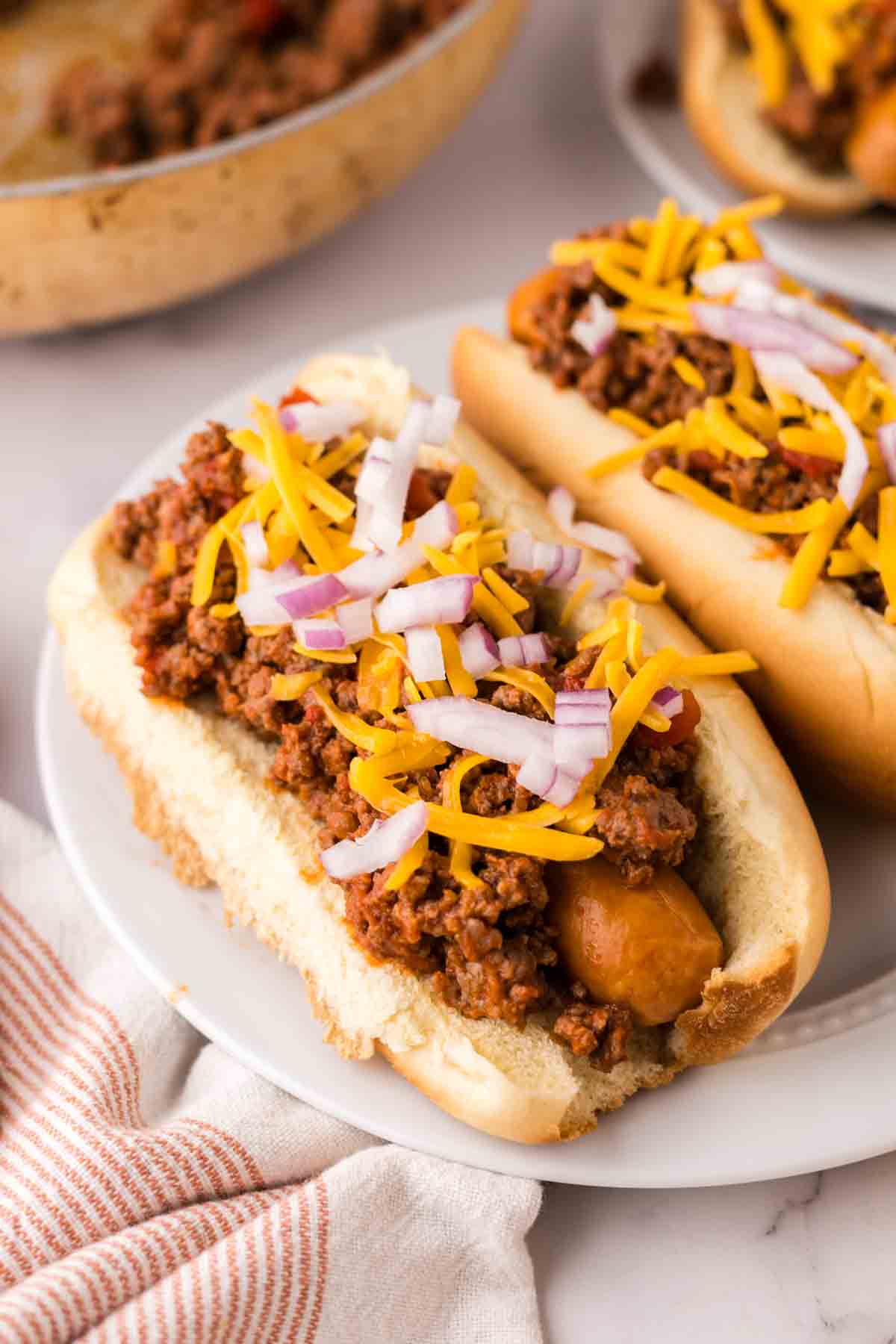 chili dogs recipe over round white plates.