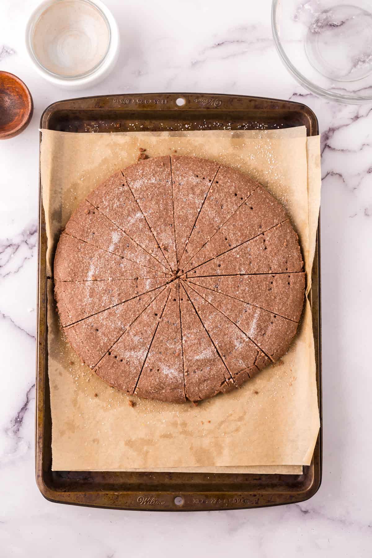 baking sheet with parchment and a delicious baked round chocolate shortbread.