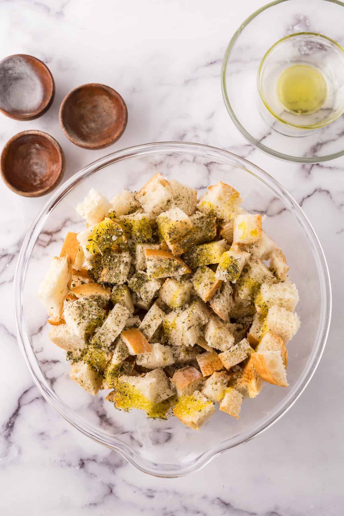 clear bowl with oil and seasonings on bread to make the crouton recipe.