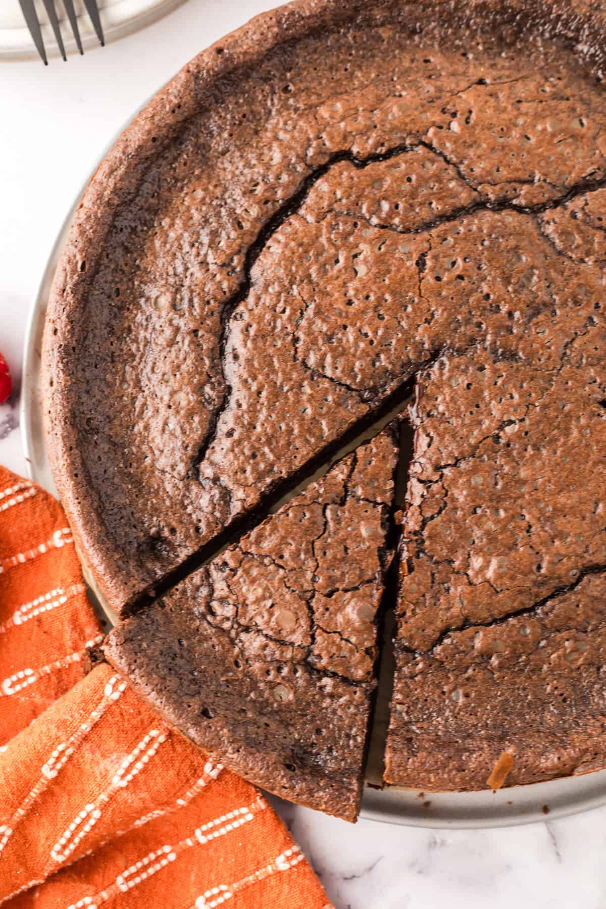 round cake pan with flourless chocolate cake and a slice ready to serve.