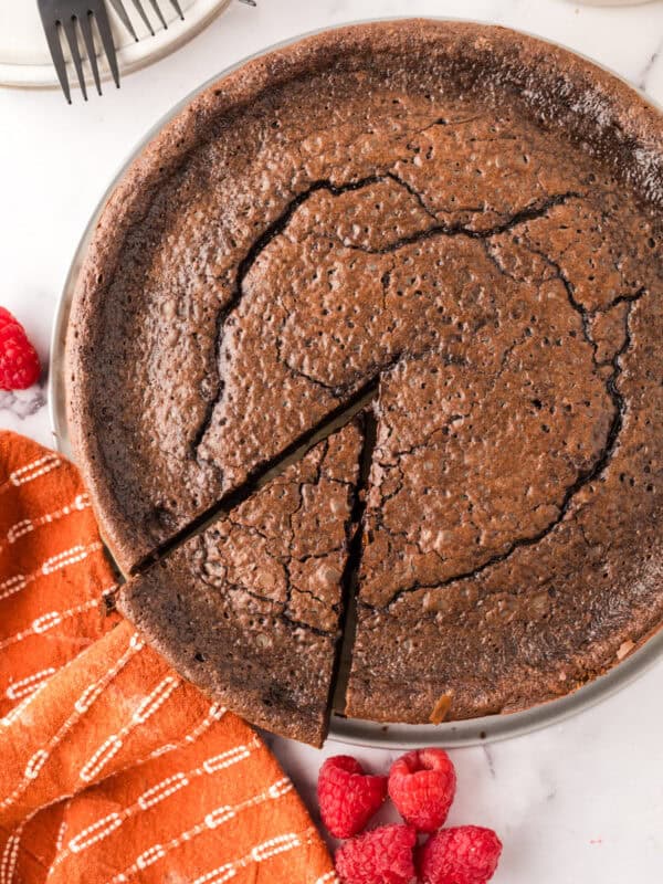 round cake pan with flourless chocolate cake and a slice ready to serve.