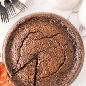 round cake pan with fresh from the oven flourless chocolate cake.