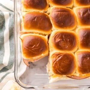 casserole dish with baked ham and cheese sliders on hawaiian rolls.