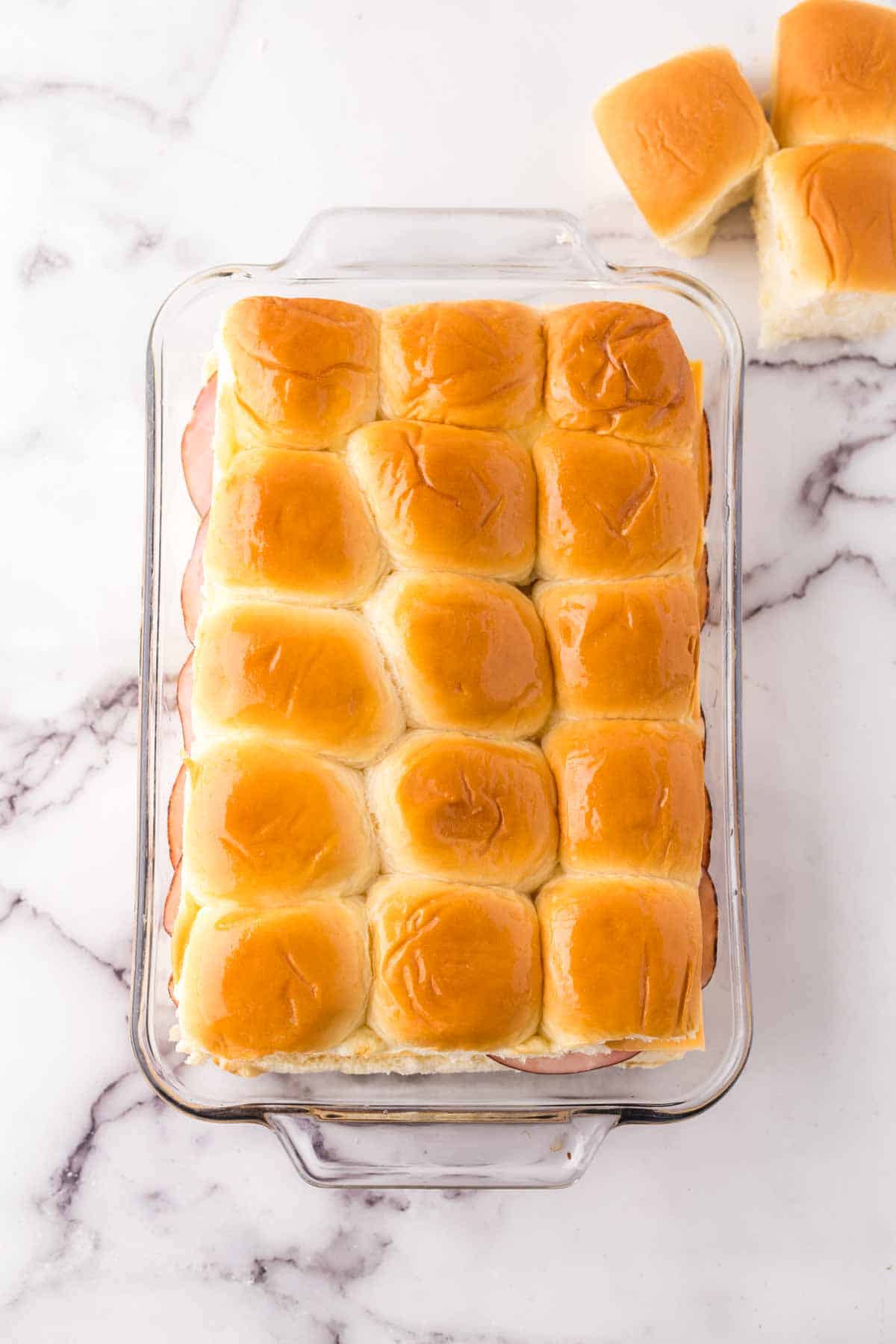 hawaiian rolls in a casarole dish going into the oven.