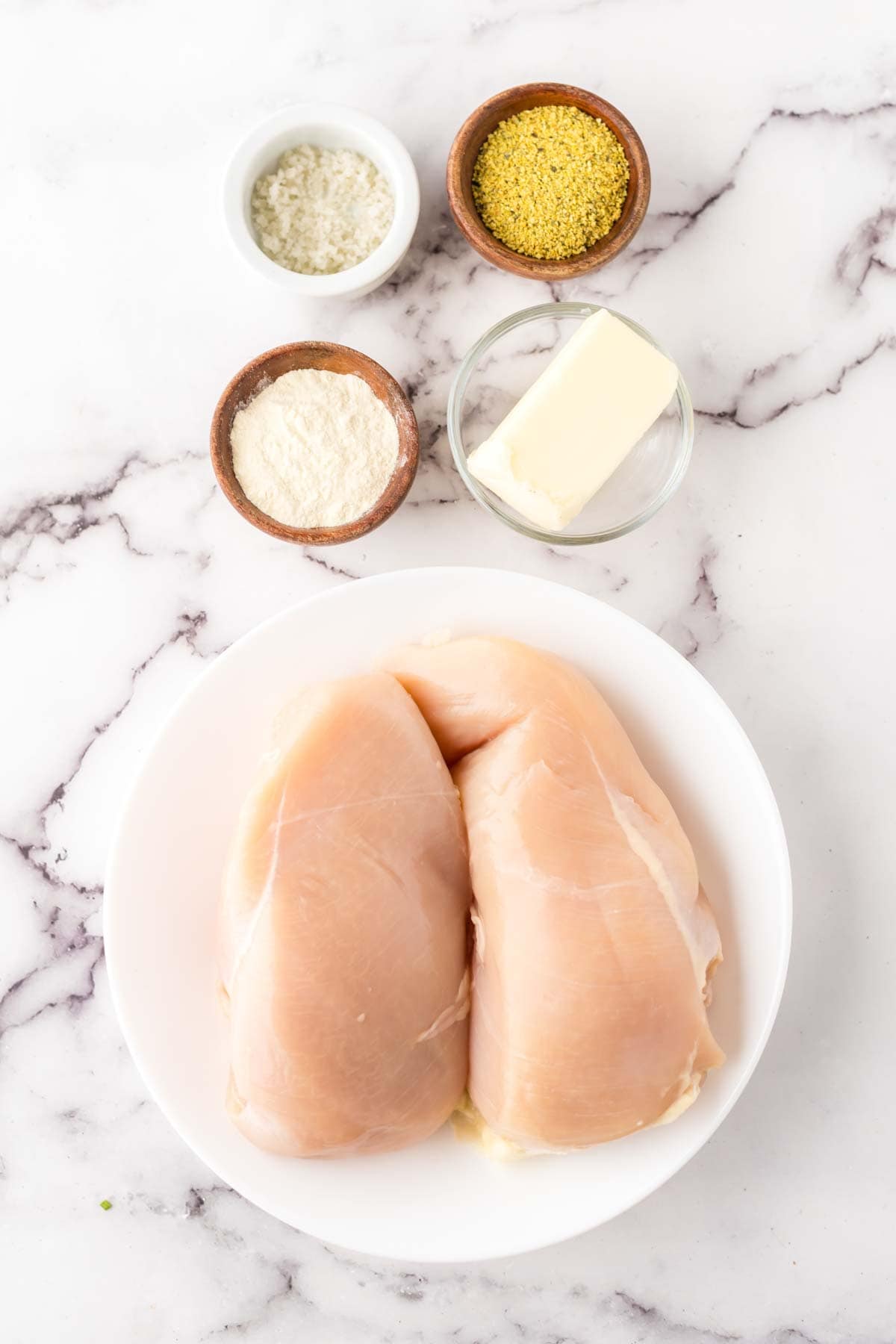 portion bowls each with raw ingredients to make the lemon pepper chicken recipe.