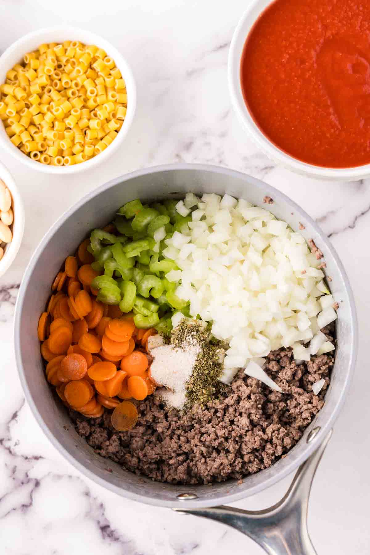 sauce pan in process of making raw ingredients into Pasta Fagioli Soup.