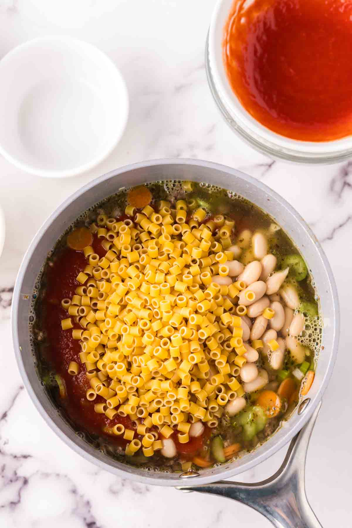 sauce pan in process of making raw ingredients into Pasta Fagioli Soup.