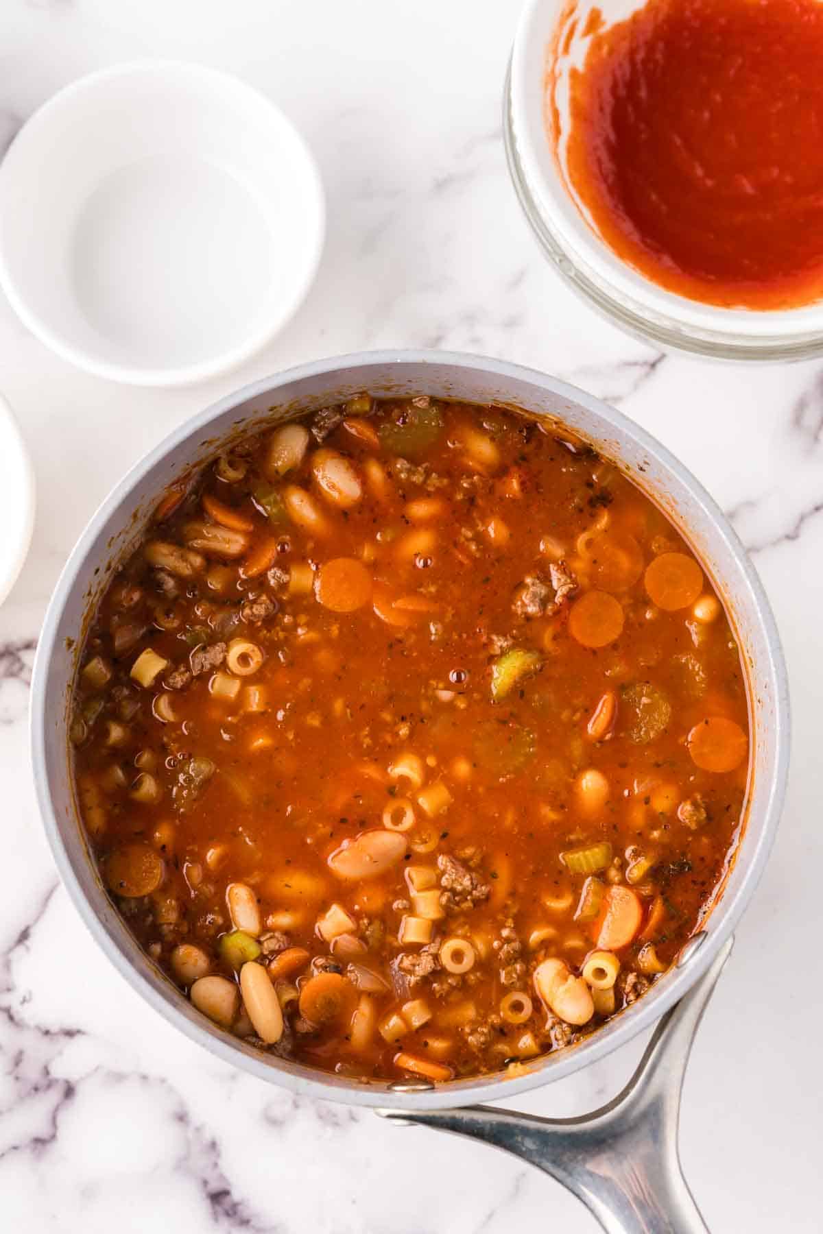 sauce pan in process of making raw ingredients into make Pasta Fagioli Soup.