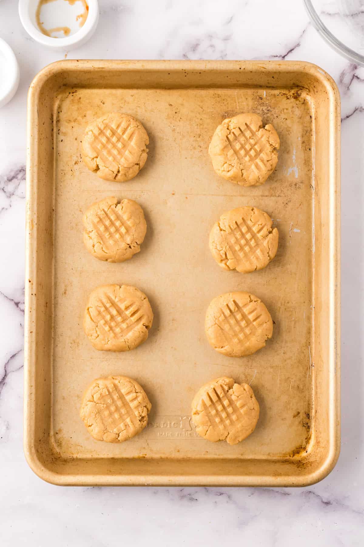 sheet pan with 8 peanut butter cookies ready to bake.