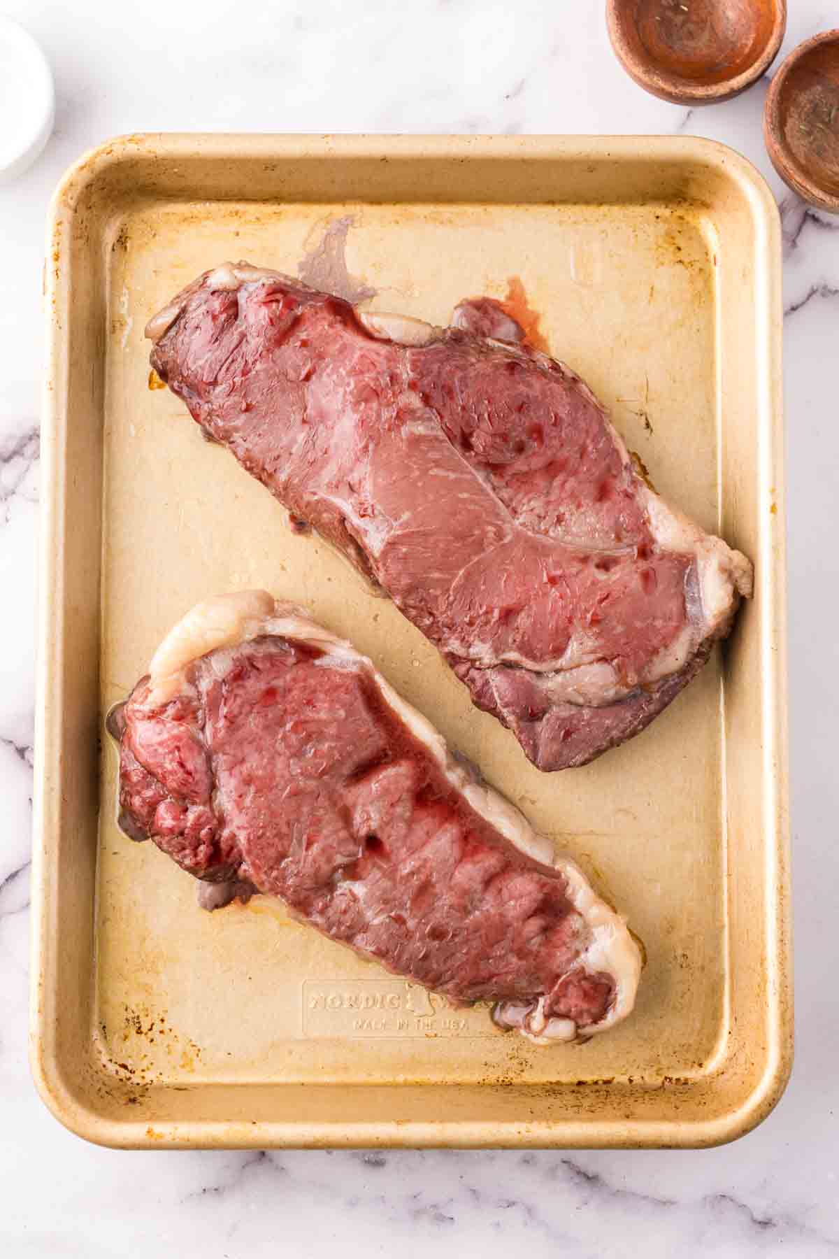 two cooked steaks on a sheet pan.