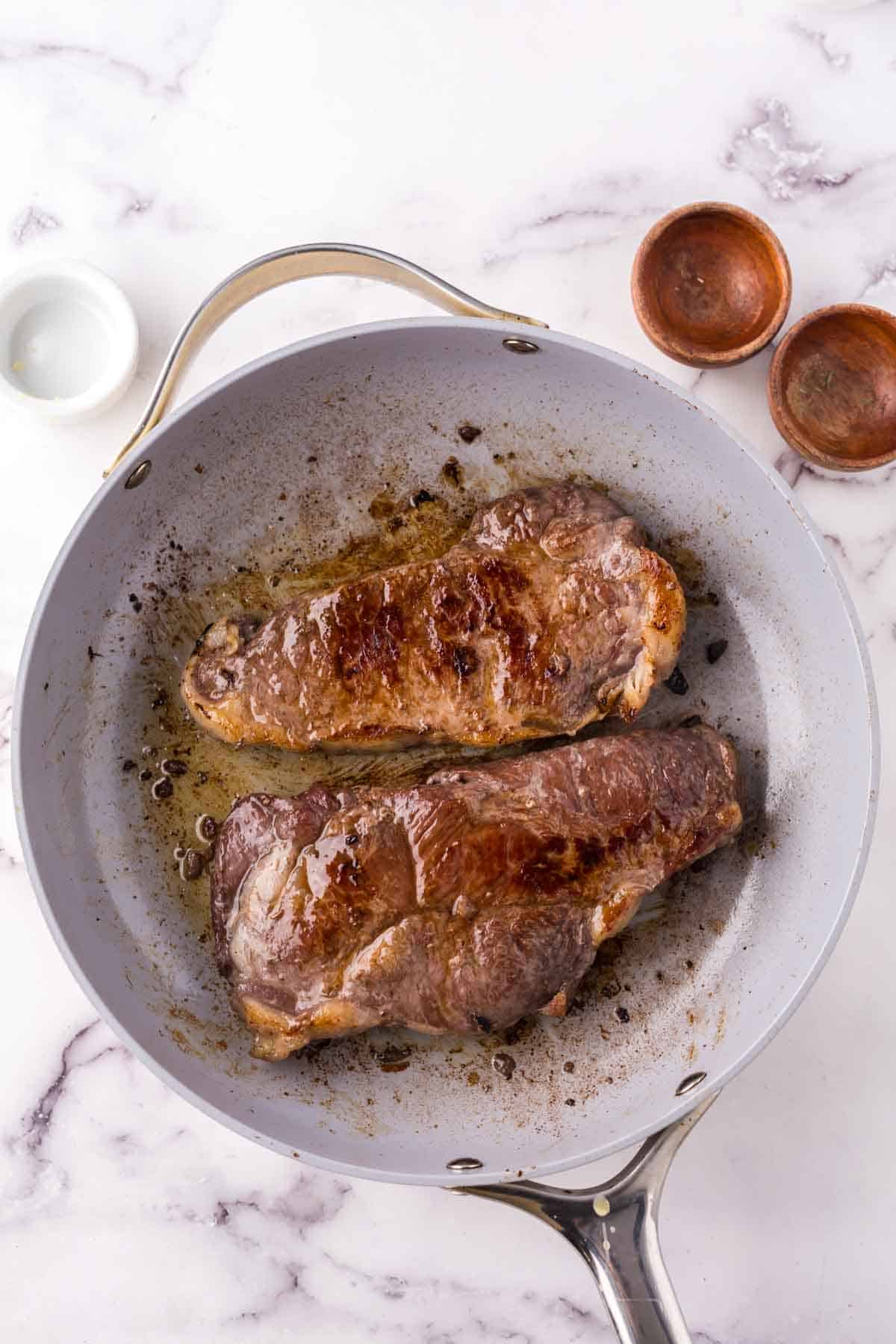 two cooked steaks in a pan.