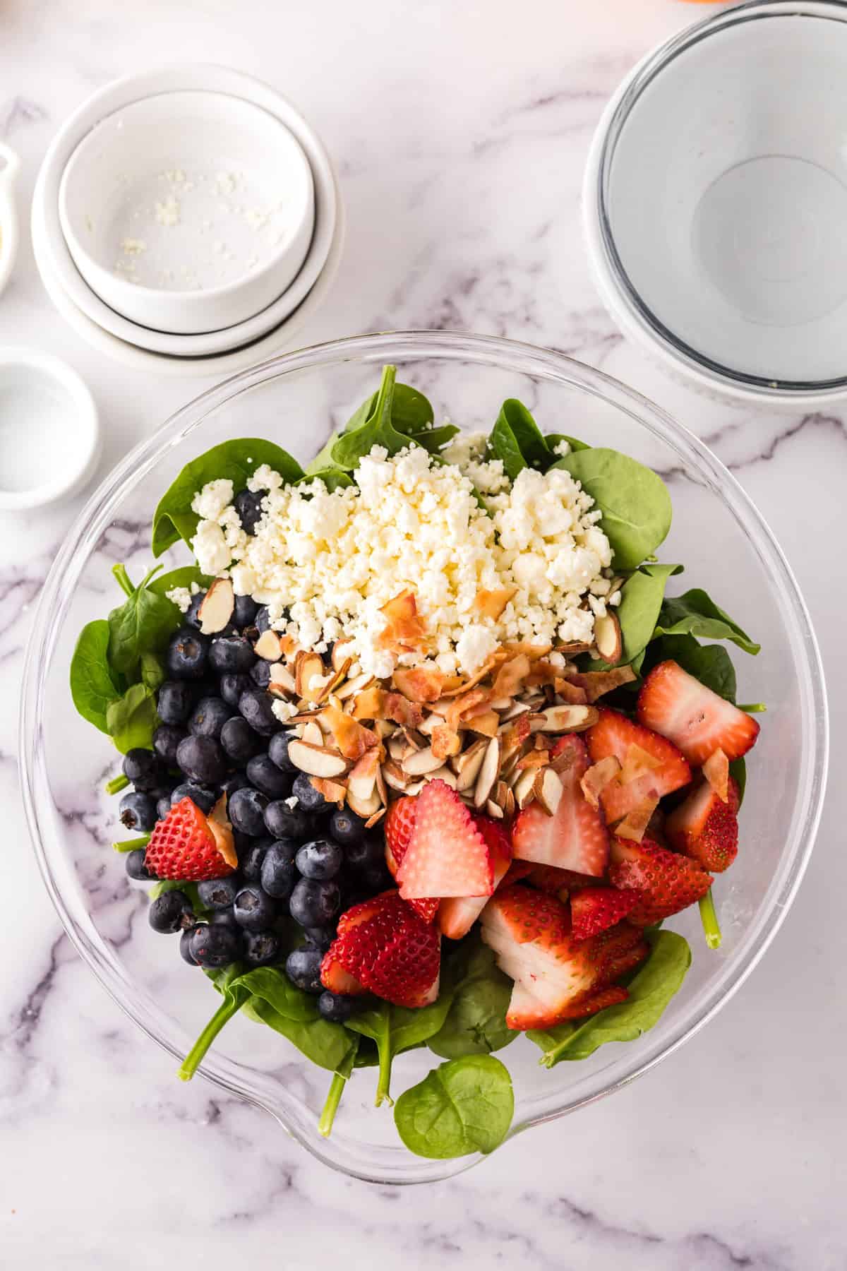 Spinach berry salad in a clear mixing bowl.